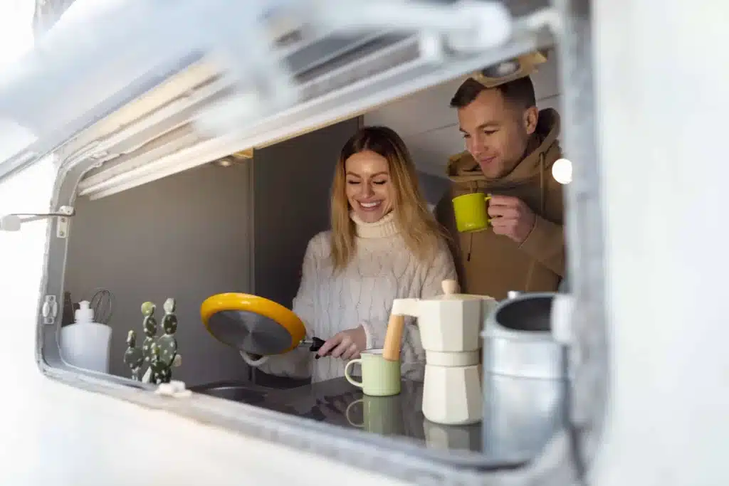 young couple smiling in their caravan kitchen