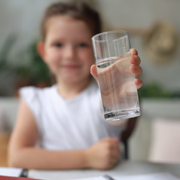 child holding glass of water towards camera